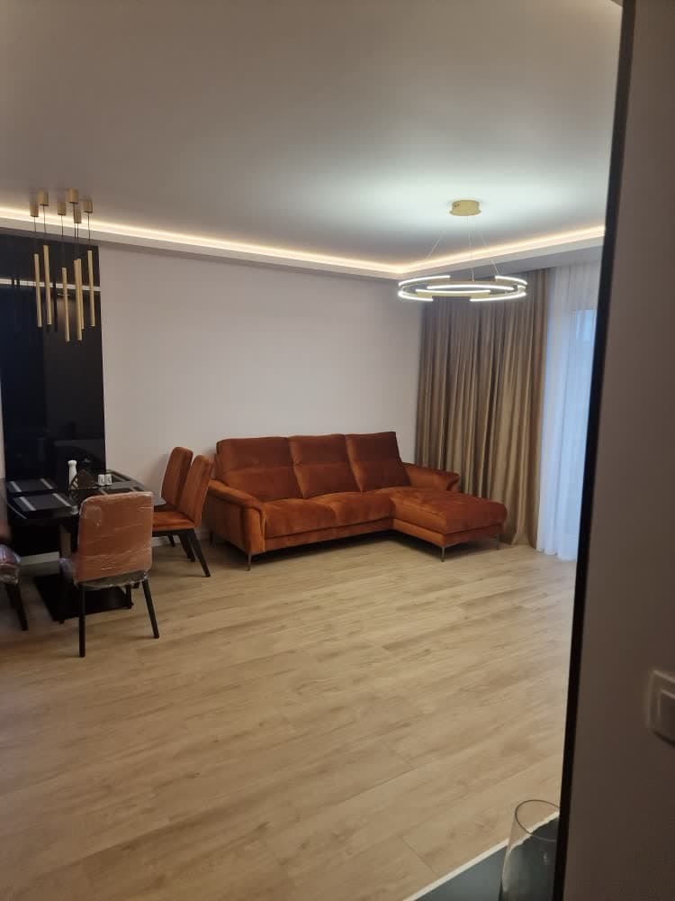 Salon z ceglastą sofą, ciemną zabudową i lampą wiszącą